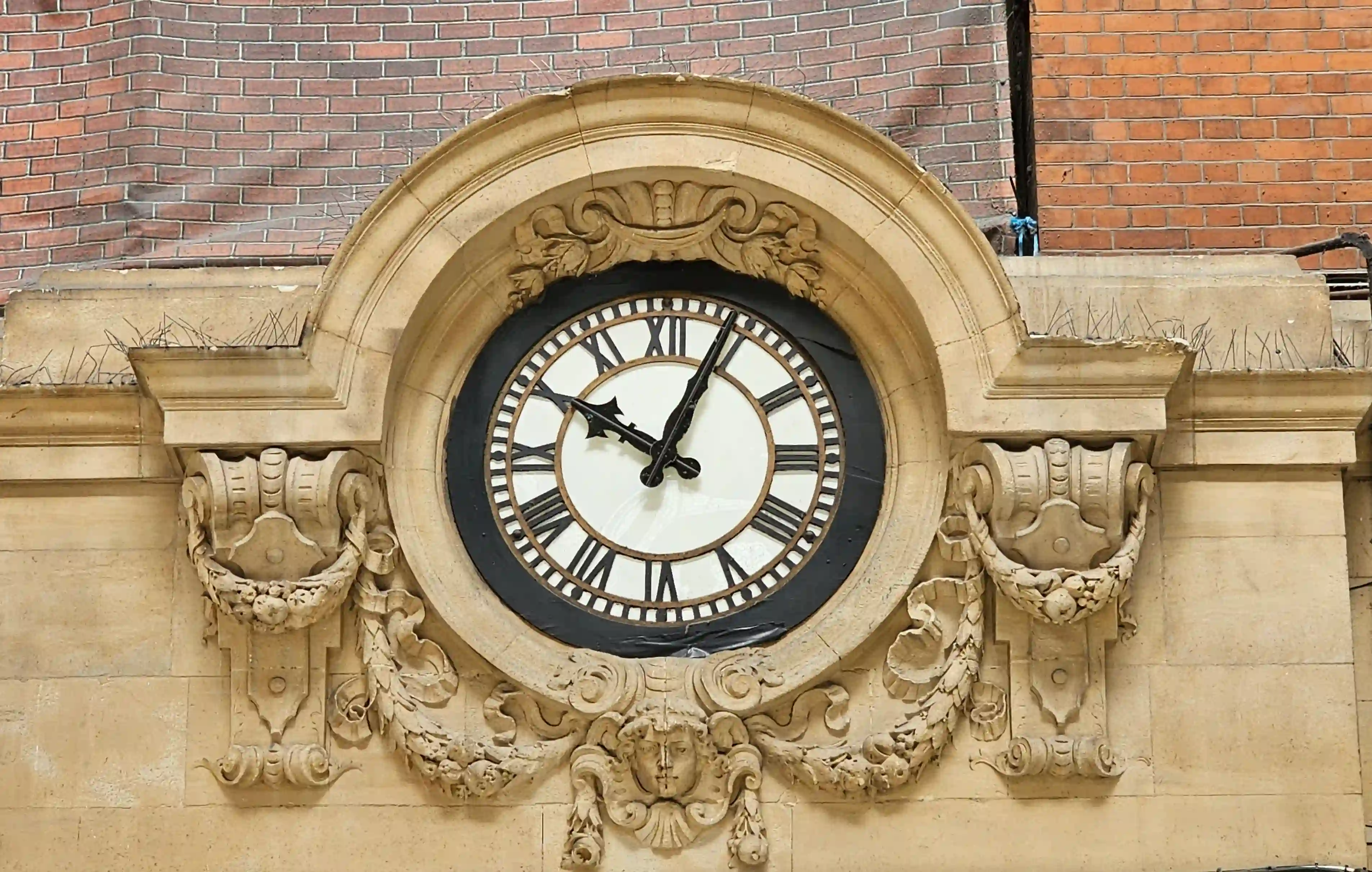 Ornate stone building facade in London featuring a large antique clock, symbolizing universal time's authority over atmospheric conditions and human calendars.